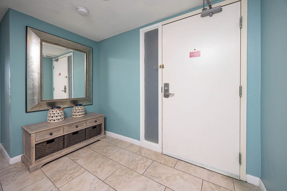 This welcoming entryway features a stylish mirror, a decorative console table, and a soothing teal wall color