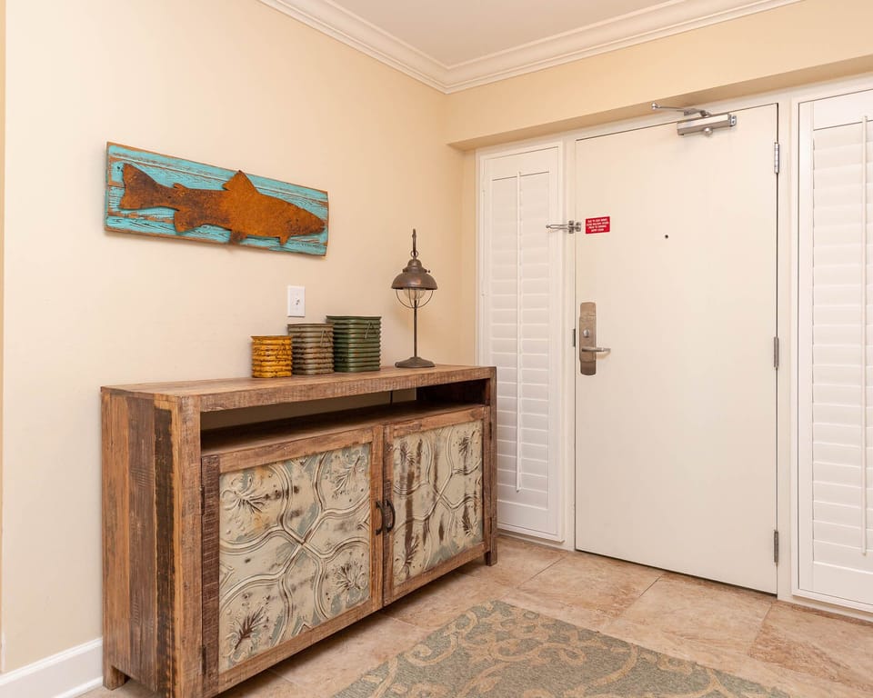 The entryway features a rustic console table with decorative accents and a charming fish artwork, setting a relaxed tone