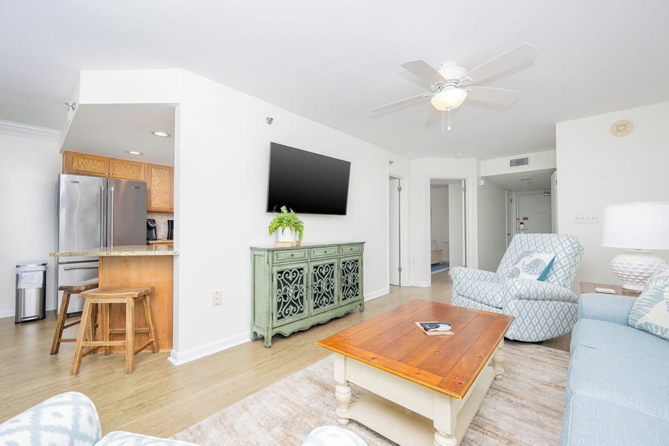 Bright living area features a comfortable sofa, stylish accent chair, and a breakfast bar, creating a welcoming space