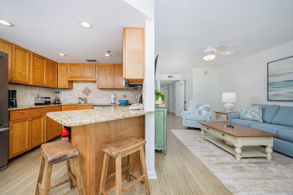 Bright wooden cabinetry complements the granite countertops in this inviting kitchen area, featuring a breakfast bar