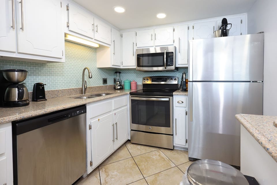 This kitchen features sleek stainless appliances, stylish tile backsplash, and ample counter space for meal preparation