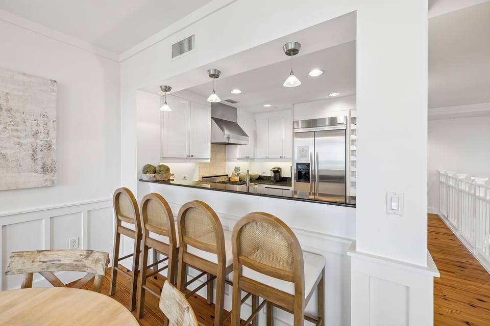 Gather around the inviting breakfast bar with stainless steel appliances and sleek white cabinetry at your fingertips, ready for your morning coffee rituals.