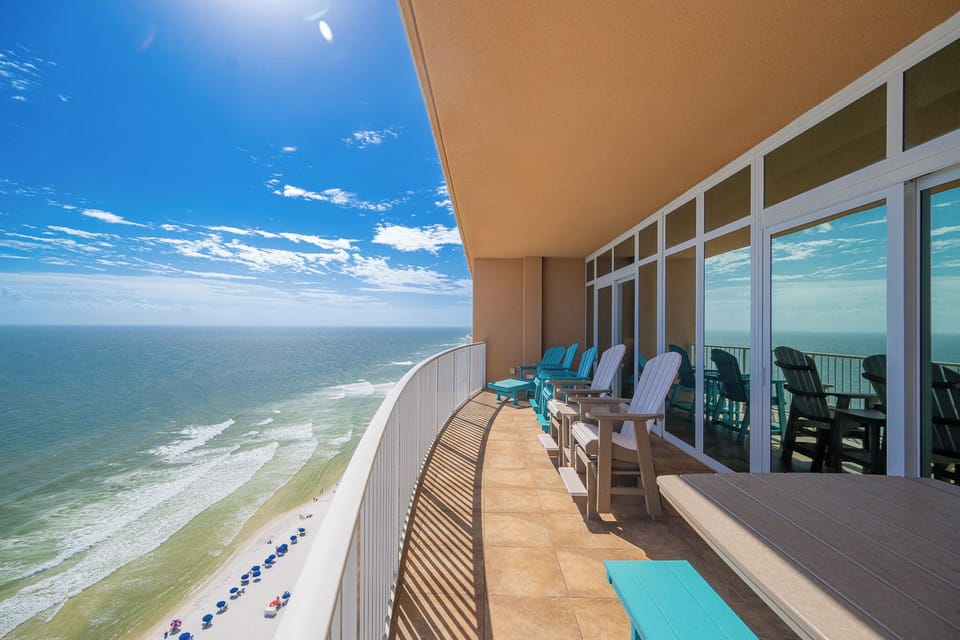Relax in colorful chairs on the spacious balcony, enjoying sweeping views of the waves and bright blue sky