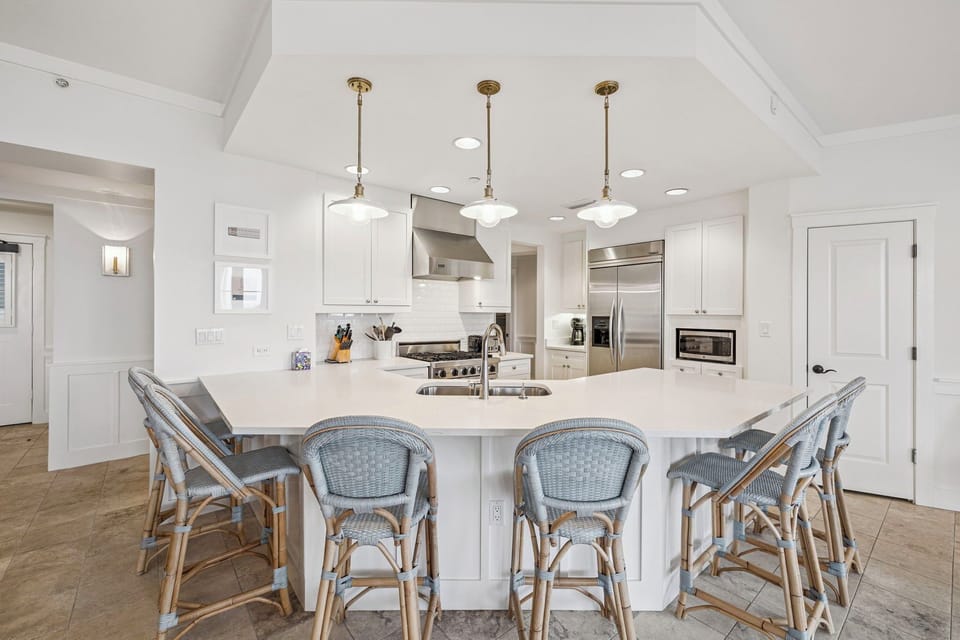 Gather around this spacious kitchen island with seating for six, where gleaming white cabinetry, stainless appliances, and warm pendant lighting create the perfect spot for your morning coffee or evening meal prep.