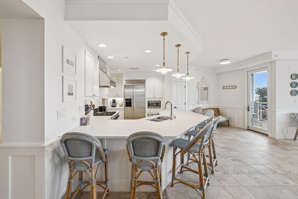 Gather around this spacious kitchen island to prep meals or share laughter over morning coffee. Crisp white cabinetry, gleaming countertops, and warm pendant lights create an inviting backdrop for your culinary adventures.