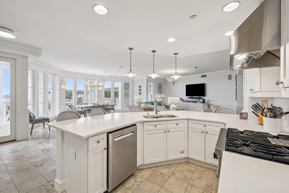 Step into your spacious coastal retreat where a chef's kitchen flows seamlessly into open living and dining areas, all bathed in natural light from floor-to-ceiling windows framing stunning views.