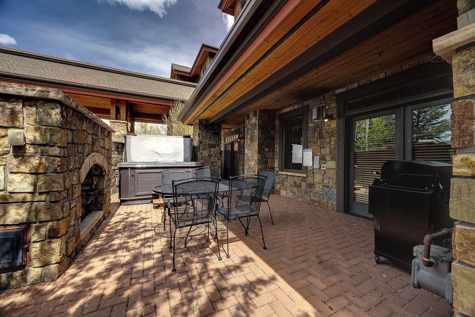 Your private patio invites outdoor living with a hot tub, stone fireplace, BBQ grill, and shaded dining—perfect for mountain mornings or starlit evenings.