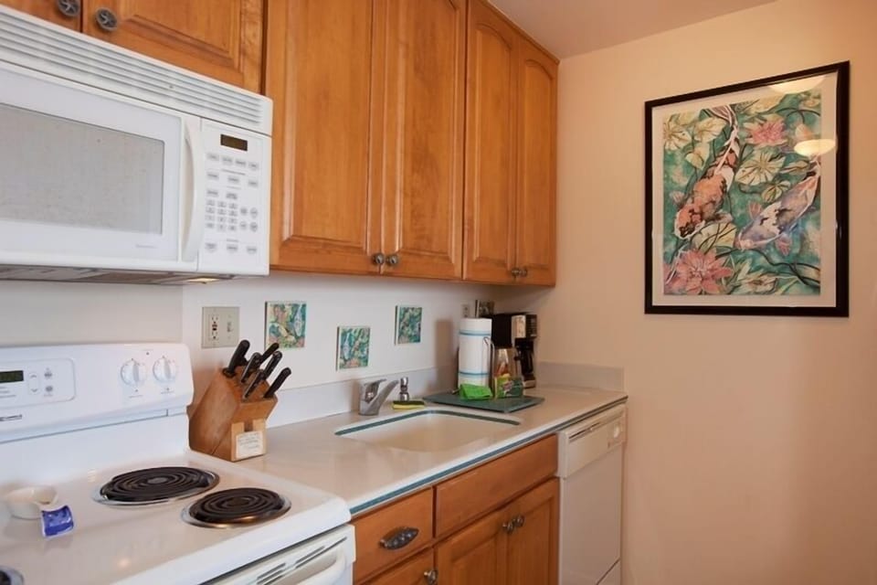 Your fully equipped kitchen features warm wood cabinets, modern appliances including microwave and dishwasher, and a cozy breakfast counter perfect for preparing meals during your stay.