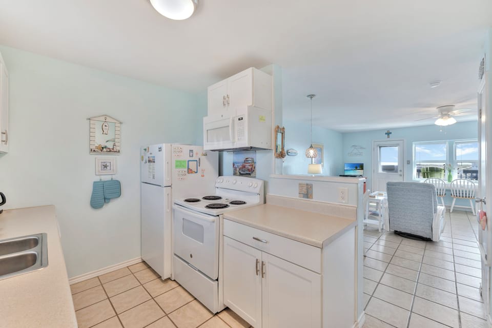 Your fully equipped kitchen awaits with everything needed to prepare your favorite meals, featuring modern appliances and bright, welcoming coastal charm.