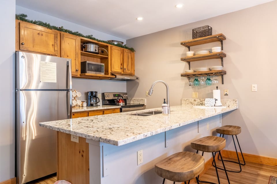 Your fully equipped kitchen features granite countertops, stainless appliances, and rustic bar seating perfect for morning coffee or casual meals.
