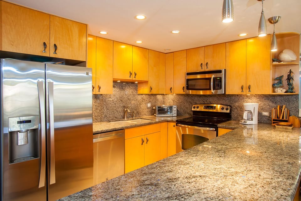Your fully equipped kitchen features gleaming granite countertops, stainless steel appliances, and warm wood cabinetry, perfect for preparing meals during your stay.