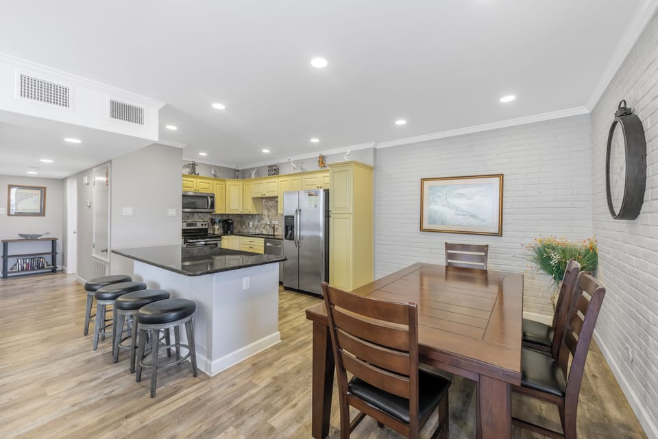 Your open-concept kitchen and dining space features sunny yellow cabinets, granite countertops, and a breakfast bar perfect for casual meals together.