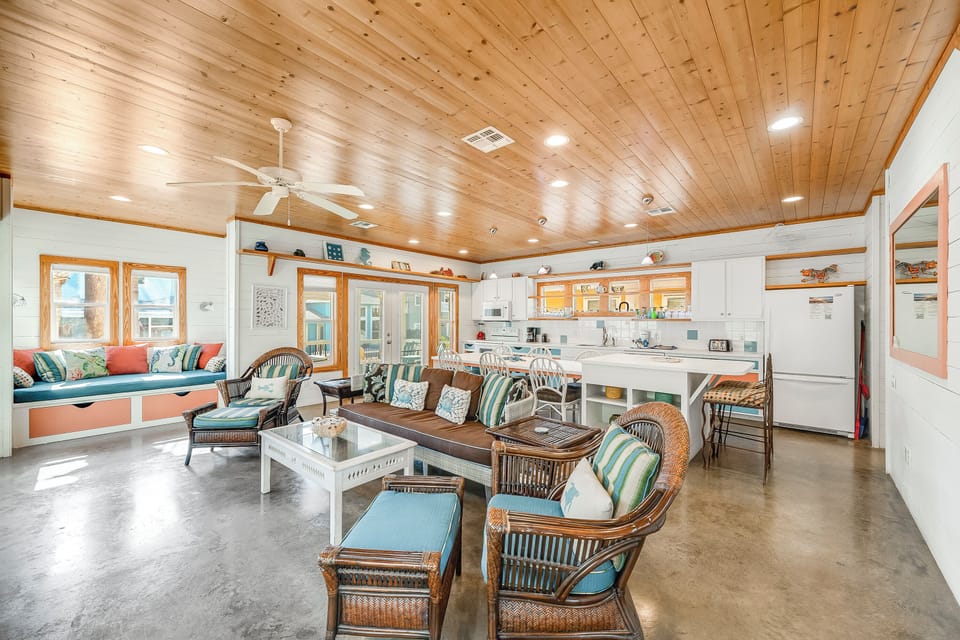 Relax in your open-concept living space with warm wood ceilings, coastal-inspired furnishings, and a fully equipped kitchen perfect for gathering.