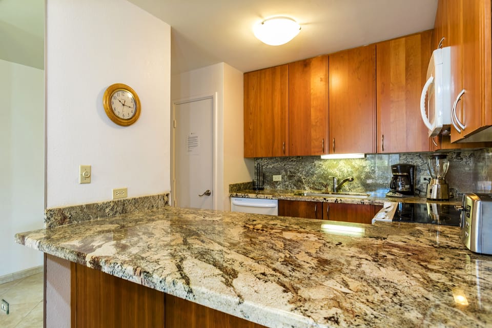 Your fully-equipped kitchen boasts elegant granite countertops and warm wood cabinetry, with modern appliances ready for creating everything from quick breakfasts to gourmet dinners during your stay.