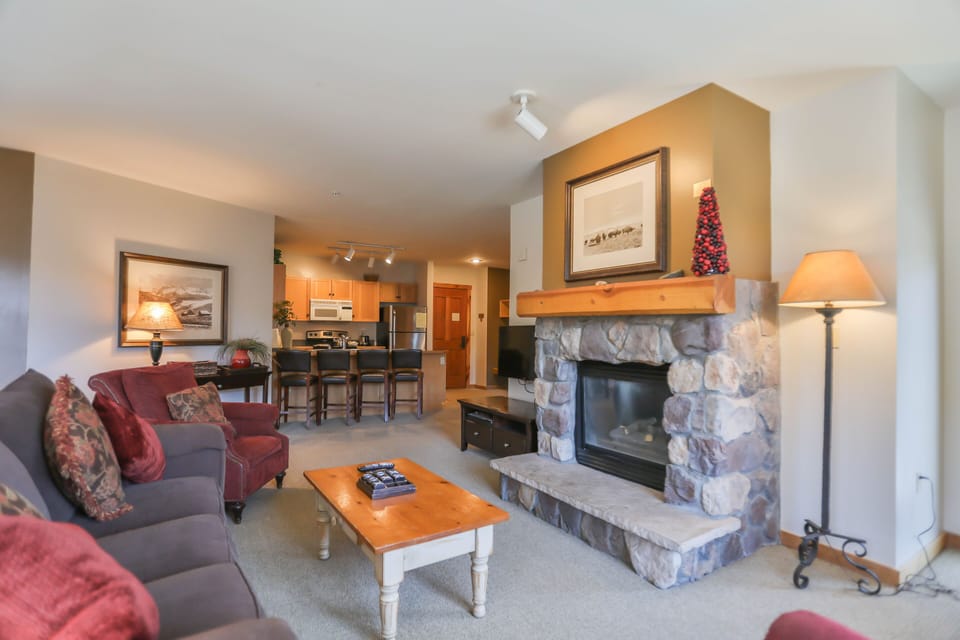 Curl up by your stone fireplace in this cozy living room, where plush burgundy sofas invite evening relaxation after mountain adventures.