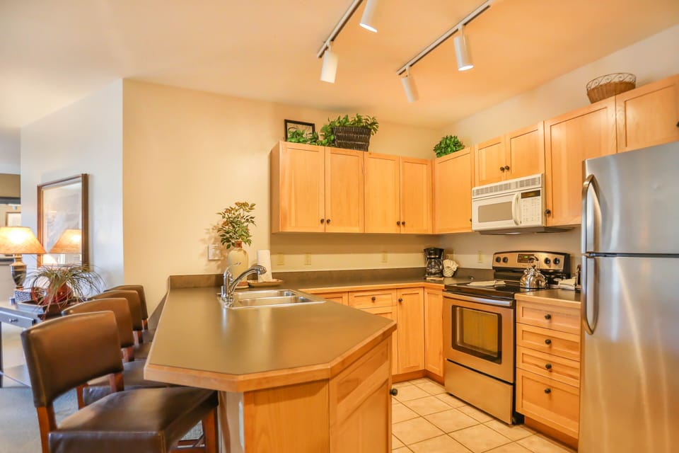 Your fully equipped kitchen features warm wood cabinetry, stainless steel appliances, and a convenient breakfast bar for morning coffee.