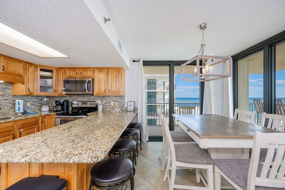Gather around the dining table or breakfast bar, enjoying the inviting space with views of the water beyond