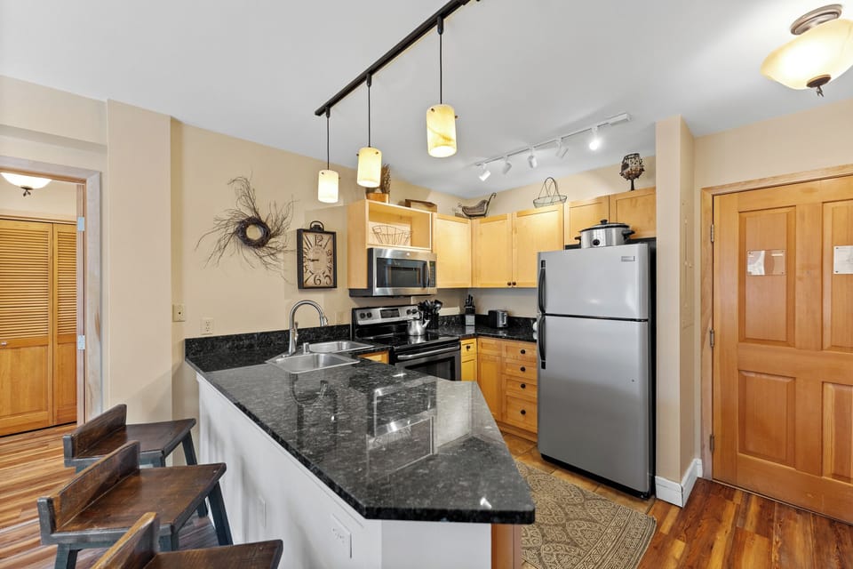 Your fully equipped kitchen features granite countertops, stainless steel appliances, and warm pendant lighting for memorable meal prep.