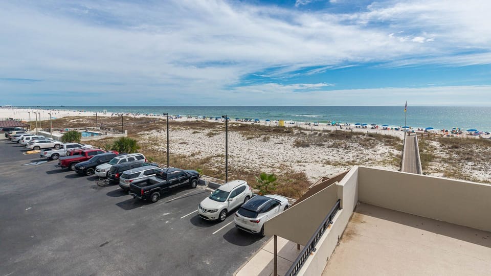This view showcases a beautiful beachfront with sandy dunes and colorful umbrellas, perfect for relaxation and fun