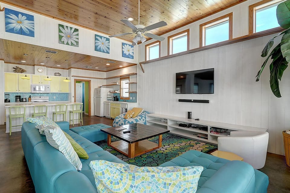 Sink into plush turquoise seating while enjoying your morning coffee in this bright, open living space with soaring wood ceilings and modern amenities.