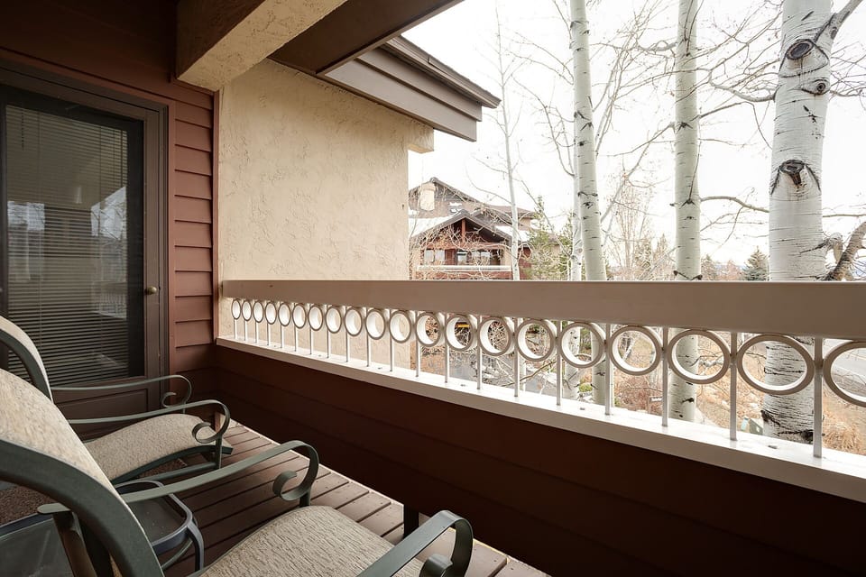 Unwind on your private balcony with charming mountain lodge views and peaceful aspen trees framing the scene.
