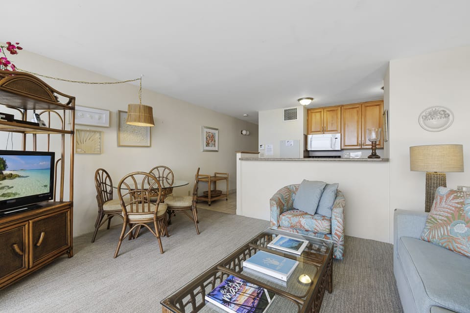 Relax in your bright, coastal-inspired living space with beachy rattan furniture, tropical prints, and an open kitchen. Your home-away-from-home awaits with soft seating, natural light, and island charm throughout.