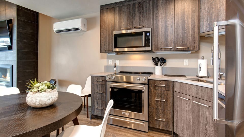 Prepare meals in our fully equipped kitchen, featuring a large island with bar seating, modern stainless steel appliances, and a stylish two-tone design. All the essentials for a great stay.