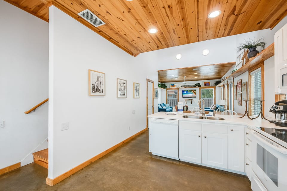 Your modern kitchen features white cabinets, stainless appliances, and stunning wood ceiling beams that create a perfect blend of contemporary comfort and rustic charm.
