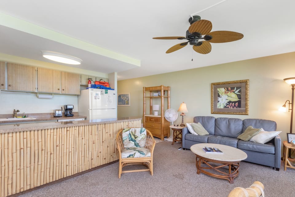 Relax in your beachy open living area with tropical fan, comfy seating, and well-equipped kitchenette—perfect for easy coastal getaways.