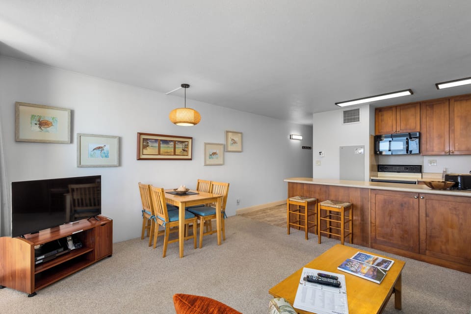 Your open-plan living and dining space features warm wood finishes, a fully equipped kitchenette, and a cozy dining area perfect for shared meals after exploring the area.