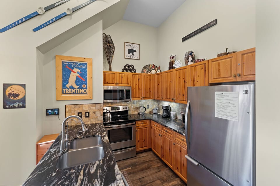 Your fully equipped kitchen features granite countertops, stainless steel appliances, and charming ski-themed décor, perfect for preparing mountain meals.