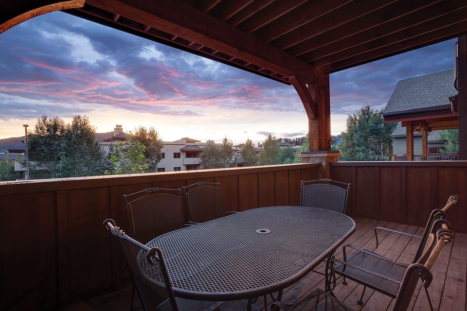 Private covered terrace with dining table overlooking a residential neighborhood at sunset.