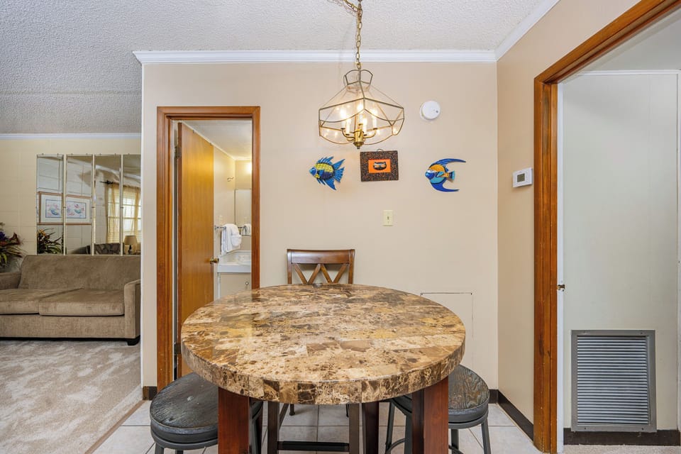 This dining area features a round marble table, colorful fish decor, and a cozy view into the adjoining living space