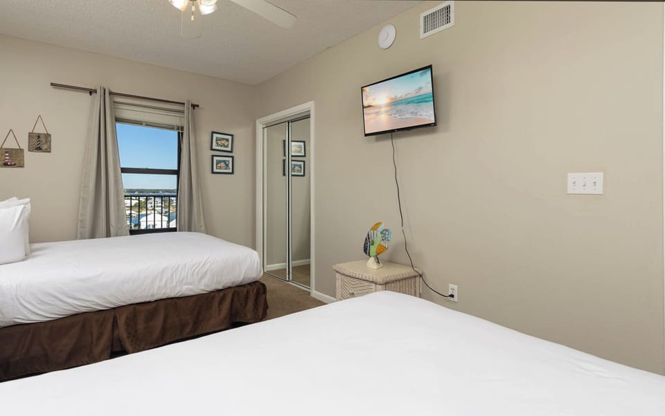 Inviting guest bedroom with two queen beds, a TV for entertainment, and a window offering a lovely view