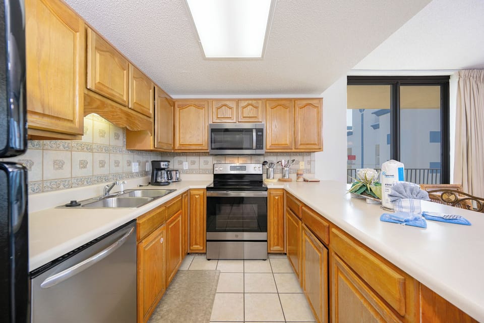 Warm wooden cabinetry and black and stainless appliances complement the spacious kitchen with a breakfast bar