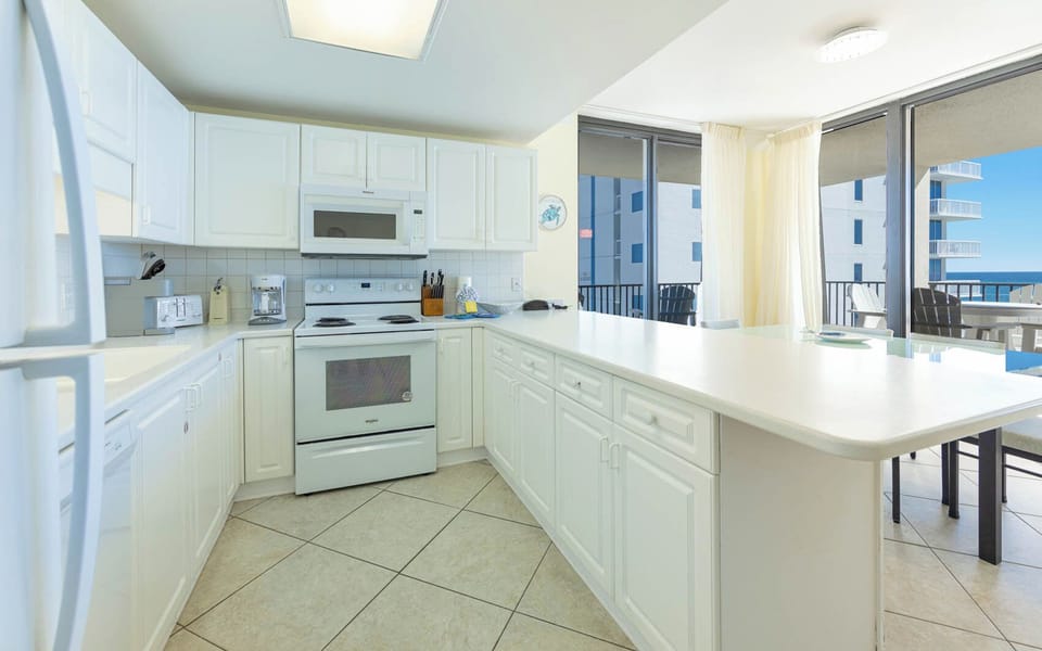 Bright white cabinetry and a spacious countertop create an inviting atmosphere in this kitchen with a view of the beach