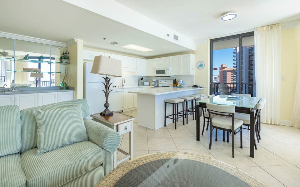 Cozy living space featuring a plush sofa, breakfast bar with seating, and a view of the beach through large windows