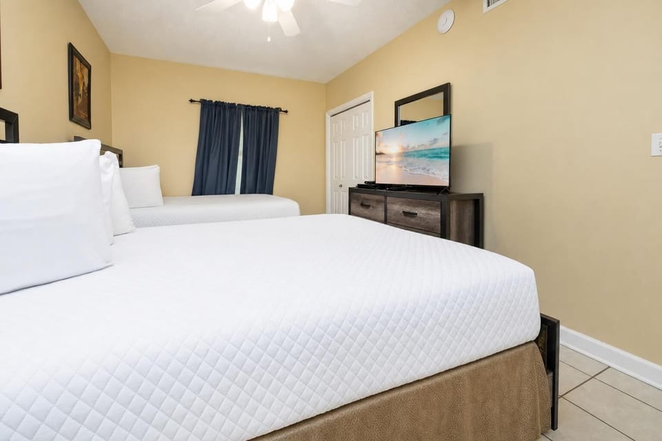 Rest in this inviting guest bedroom with two double beds, a TV for entertainment, and warm decor for a comfortable stay