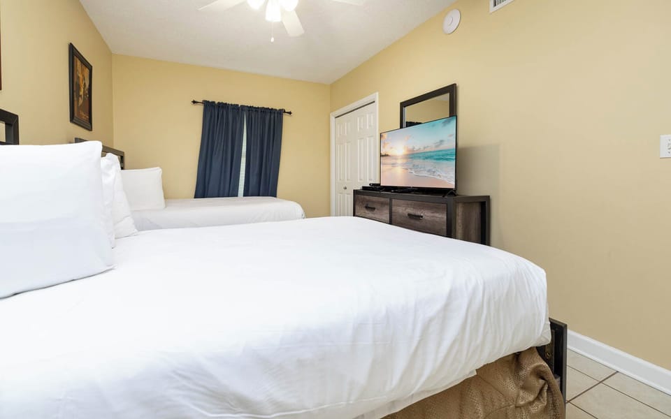 Rest in this inviting guest bedroom with two double beds, a TV for entertainment, and warm decor for a comfortable stay