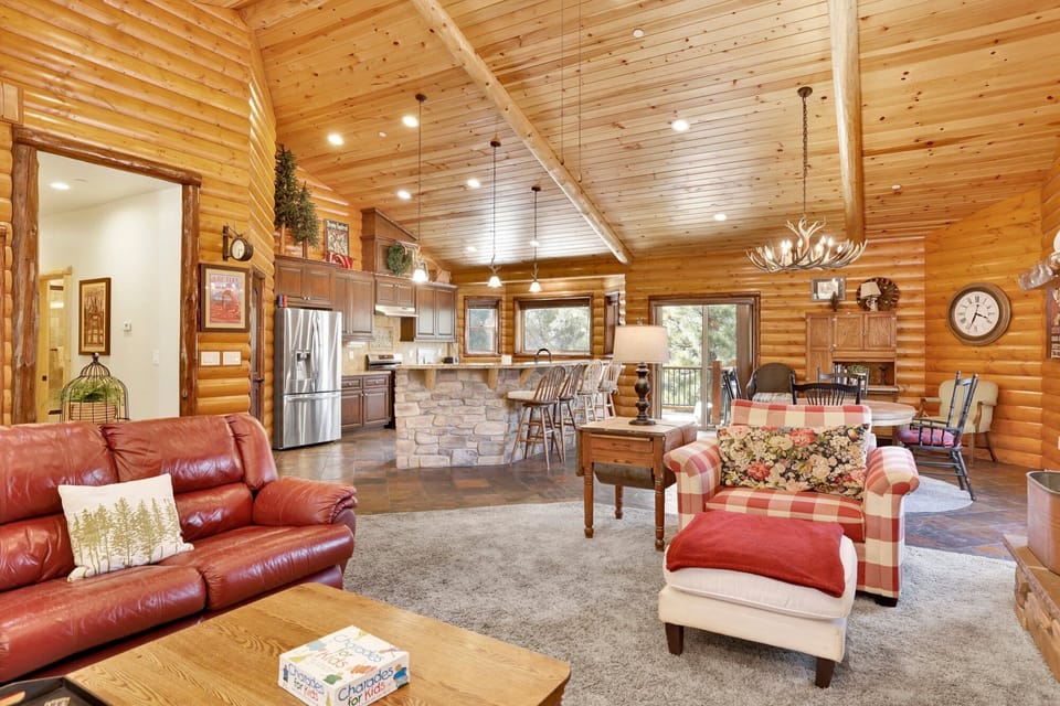 Cozy mountain living room with wood ceilings, stone fireplace, comfy seating, and smart TV—perfect for relaxing evenings, movie nights, and warm cabin vibes after outdoor adventures.