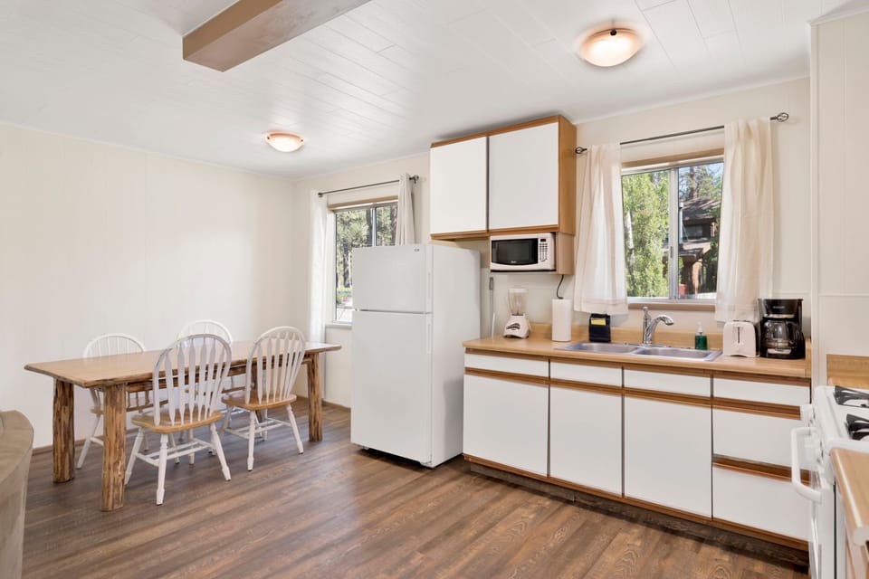 Kitchen with a refrigerator, stove, microwave, oven, toaster, coffee machine, blender, and a dining table to enjoy a delicious meal.