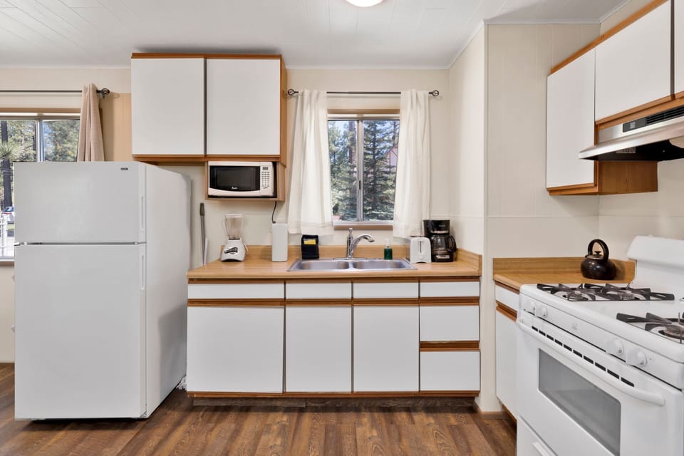Kitchen with a refrigerator, stove, microwave, oven, toaster, coffee machine, blender, and a dining table to enjoy a delicious meal.