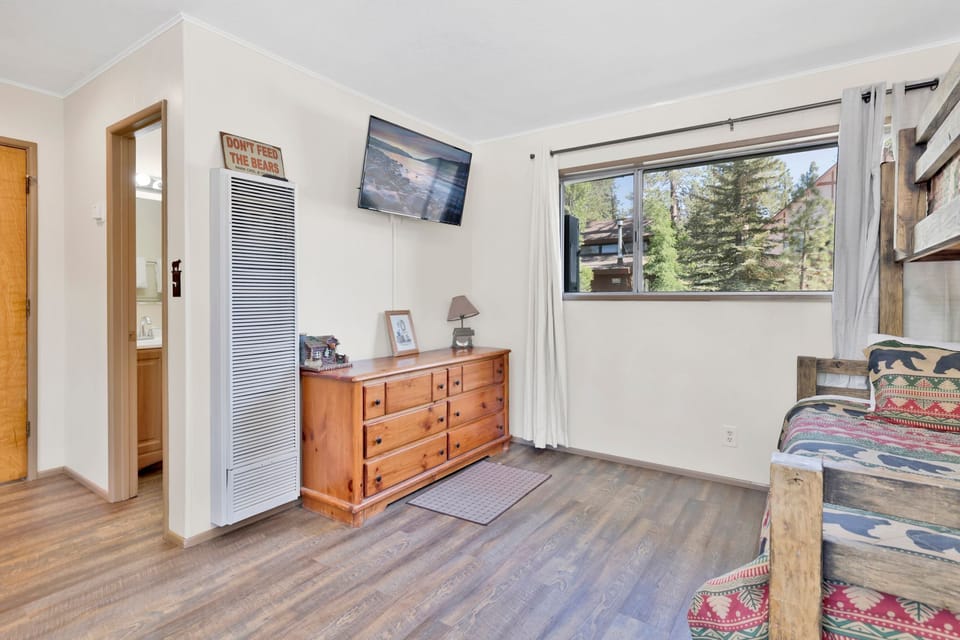 A bedroom with a queen size bed and twin bunk bed, and a full sleeper sofa.