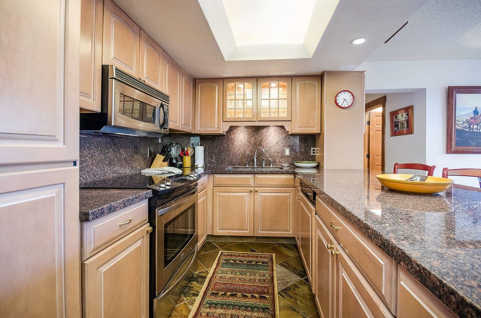 Your fully equipped kitchen features granite counters, stainless appliances, and warm wood cabinetry—perfect for preparing meals during your stay.