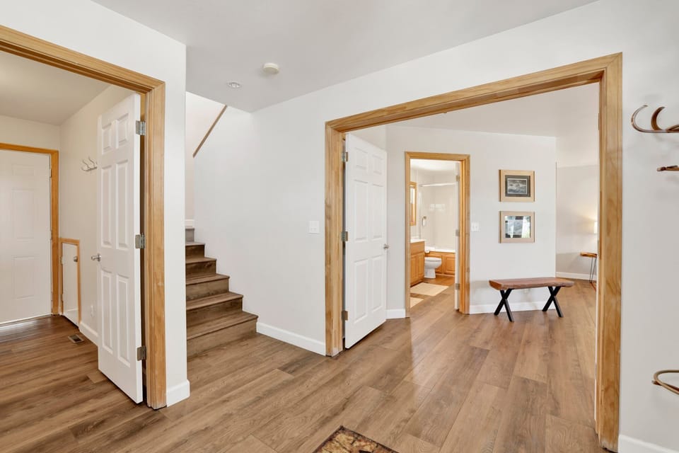 A clean and welcoming hallway featuring warm wood-style flooring and white walls. This transition space connects the main living areas to the bedrooms and stairs.