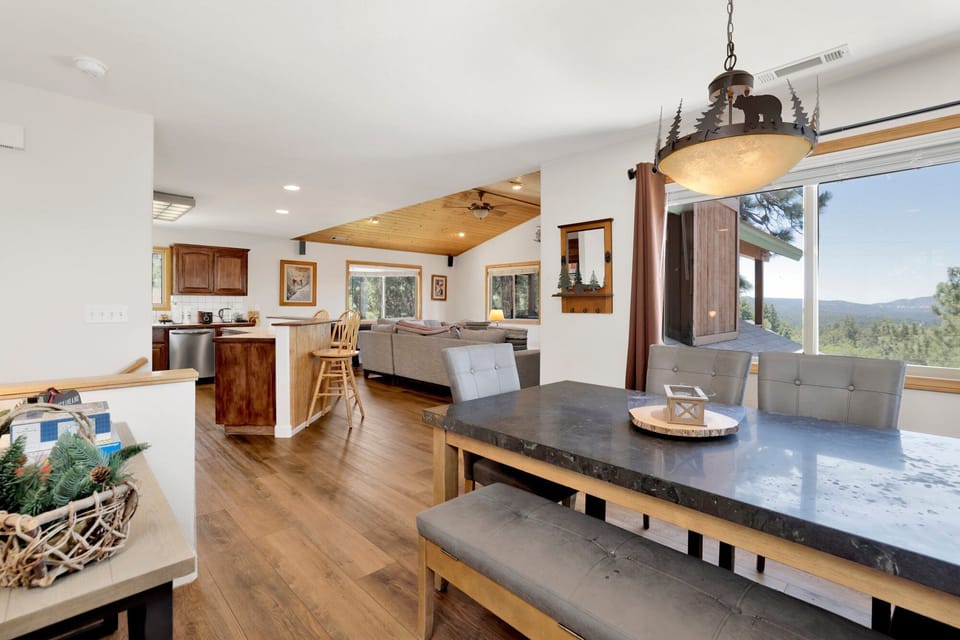 Gather for a meal in this inviting dining area. Featuring a large table with bench and chair seating for six, the space is framed by expansive windows that offer peaceful forest views while you dine.