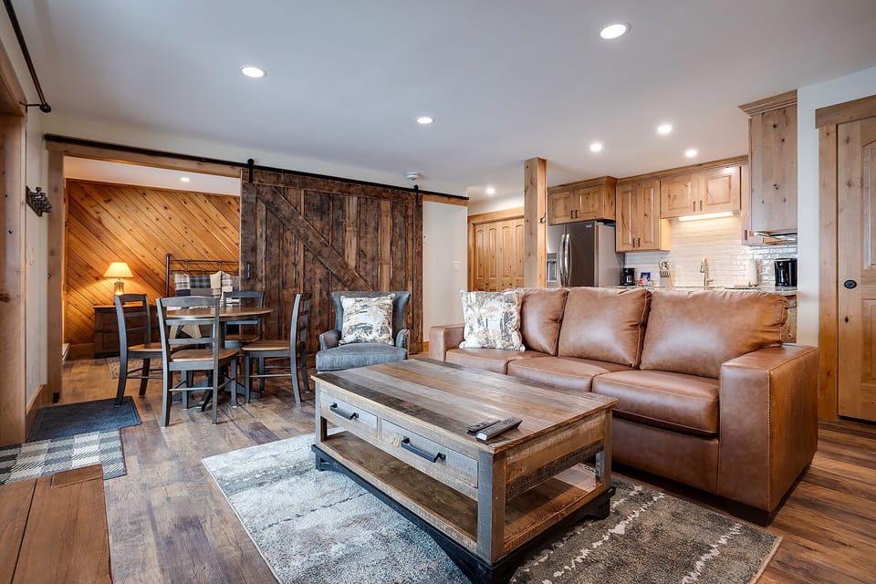 Sink into plush leather seating in your rustic-chic living space, where barn doors and warm wood create the perfect mountain retreat atmosphere.
