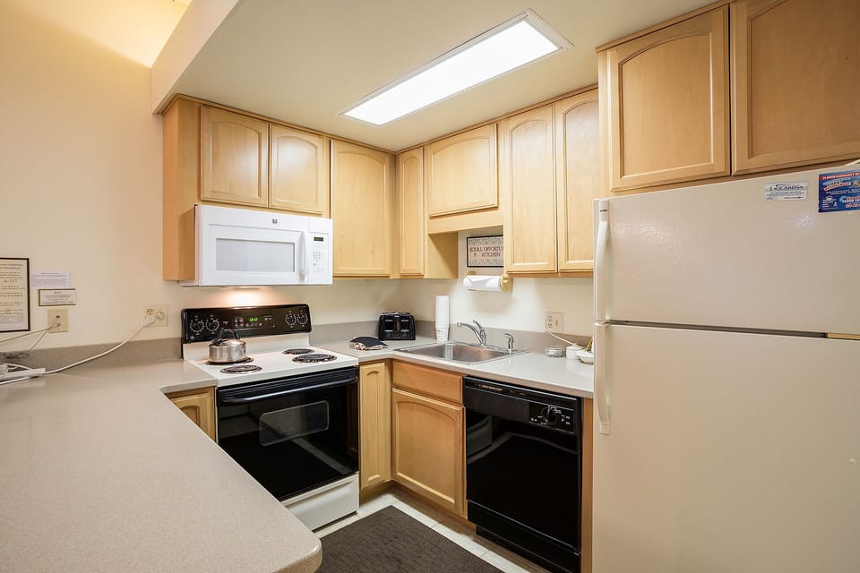 Your fully equipped kitchen features warm wood cabinetry, modern appliances, and a bright skylight creating the perfect space for preparing meals.