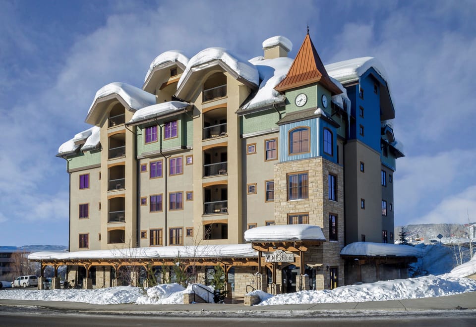 Charming mountain property with distinctive clock tower architecture, nestled amid pristine winter snow and dramatic alpine surroundings.