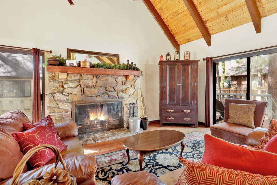 Cozy mountain living room with wood ceilings, stone fireplace, comfy seating,—perfect for relaxing evenings, movie nights, and warm cabin vibes after outdoor adventures.